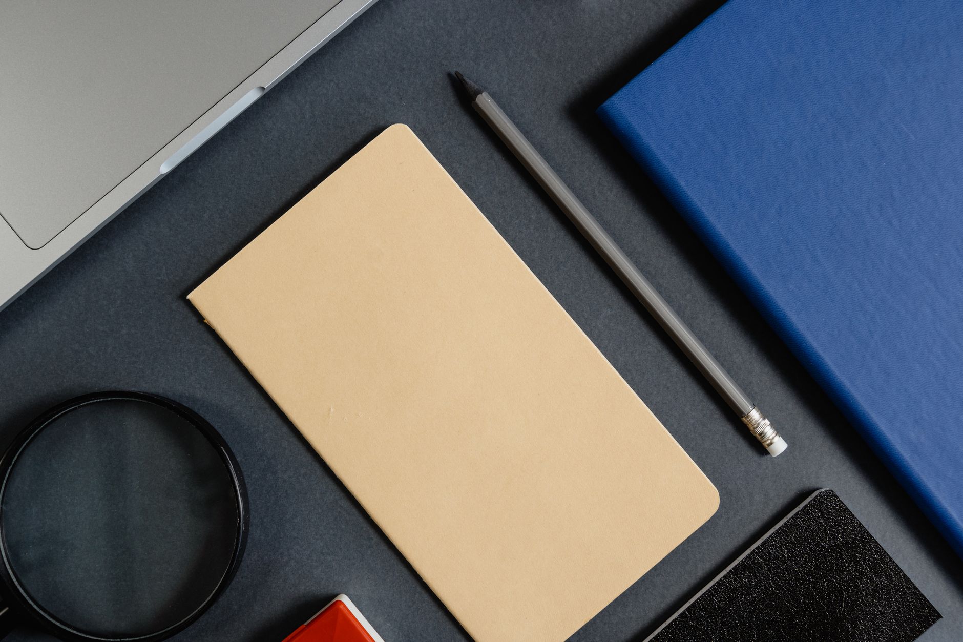 Flatlay van kantoorbenodigdheden in minimalistische stijl op een donkere achtergrond.